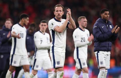 England football captain Harry Kane clapping his hands, looking down lens surrounded by team