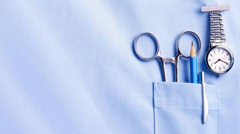A picture of a nurse's pocket with scissors, a pencil, a pen and a watch in it.