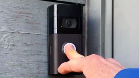 Someone pressing the button on a video doorbell