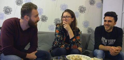 Three young adults sit on a sofa