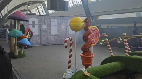 a few props including a large candy cane and large mushrooms sit in a largely empty warehouse during the Wonka event