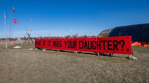 A sign is displayed at the entrance of a makeshift camp near the Prairie Green landfill in Winnipeg, Manitoba, Canada, on April 27, 2024.