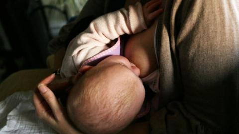A news agency photo of a mother breastfeeding a newborn baby.