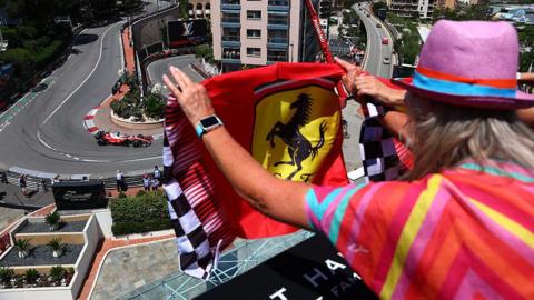 A fan holds up a Ferrari flag as Charles Leclerc drives through the hairpin in Monaco 