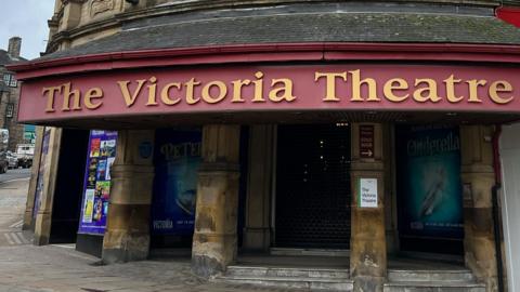 The outside of the Victoria Theatre in Halifax - a grand stone building with red and gold signage above the front
