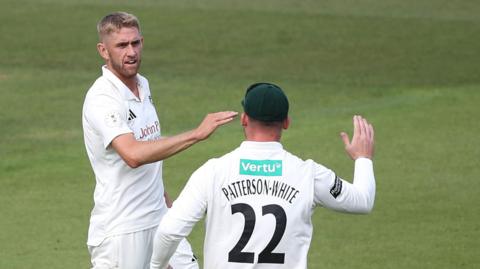 Olly Stone and Liam Patterson-White celebrate a Surrey wicket