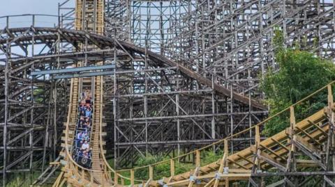 Oakwood rollercoaster with carriages of people visible coming to the bottom of one of the bends