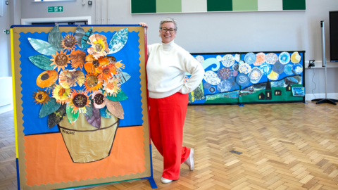 Head teacher standing with pupil art.