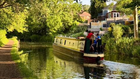 Barge on canal with sunshine through trees