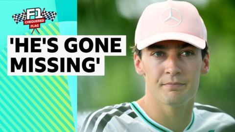 George Russell close up. He is wearing a pale pink cap with a Mercedes logo on it. 