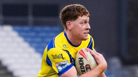 Dan Russell with the ball under his right arm, during a match for Warrington in 2025