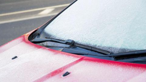 A red car with an icy windscreen.