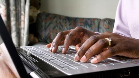 A woman typing on a laptop keyboard