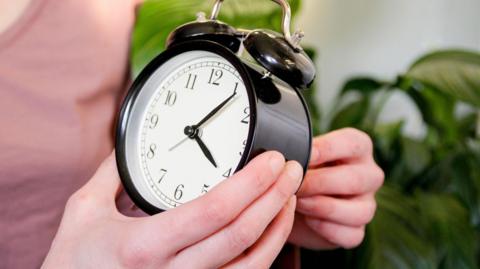 Hands winding an alarm clock