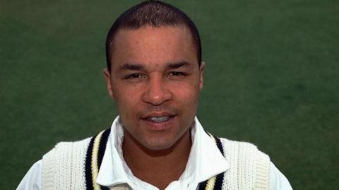 Head shot of Keith Piper wearing his white Warwickshire cricket jumper and shirt.
