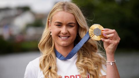Hannah Scott displaying her Olympic gold medal, with blue ribbon attached