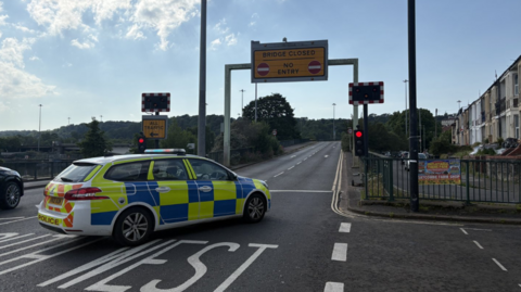 A police car sits on the slip road going up to Plimsoll Bridge.