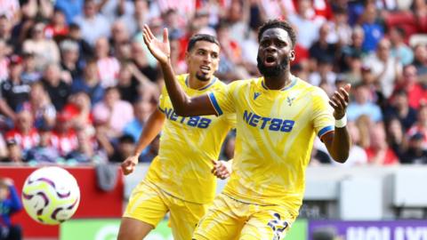 Odsonne Edouard throws his arms out in frustration as he watches the ball bounce away. He is wearing Crystal Palace's all yellow kit. 