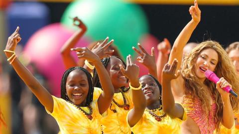 Ghetto Kids and Shakira smile as they perform together at the World Cup final's halftime show.
