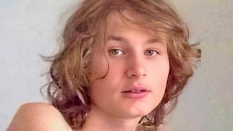 Daniel has medium length brown hair and is looking at he camera