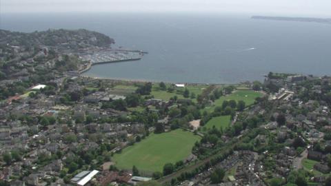 An aerial shot of Torbay with grass and the sea with the harbour seen on the left