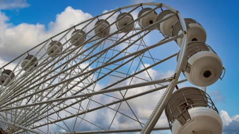 looking up through the spokes of a white Ferris wheel.