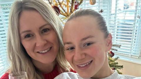 Jane Coates is standing next to her daughter Lucy Harrison is a selfie taken in front of a Christmas tree in the living room. 