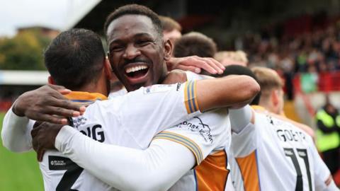 Toto Nsiala celebrates with team-mates after scoring for Shrewsbury