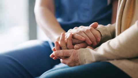 Close up of two people holding hands in comfort.