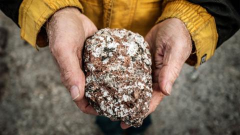 Geologist Greg Barnes holds up a rock containing crystals at the mining site, near Narsarsuaq, the gateway settlement to southern Greenland.