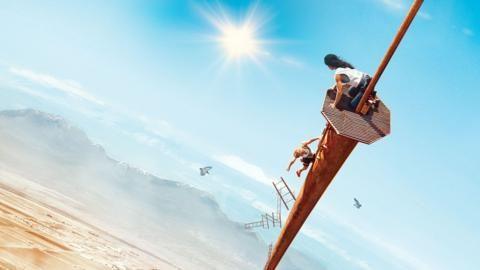 Two people in a precarious position on a very tall tower in the desert