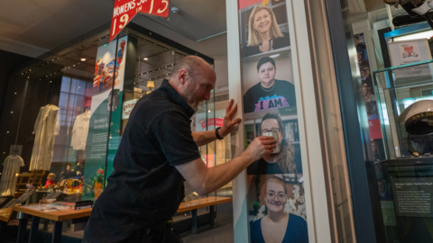 A man pasting down the portraits to a pillar inside the town hall.