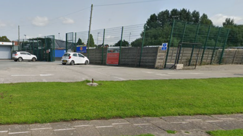 The front entrance to Avro's stadium with a handful of cars in the car park