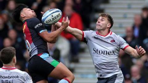 Marcus Smith of Harlequins and Tobias Elliott of Saracens contest a high ball 