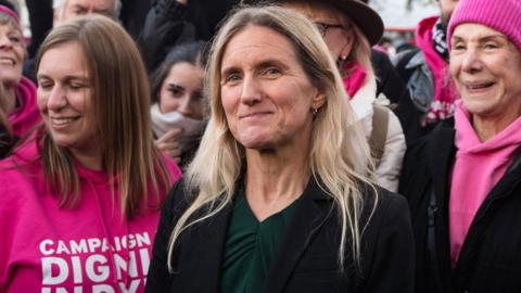 Kim Leadbeater standing alongside campaigners wearing pink outside Parliament