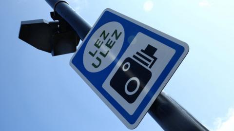 A file image showing a view of a black pole-mounted Ulez camera and blue, black and white Ulez camera sign taken from below