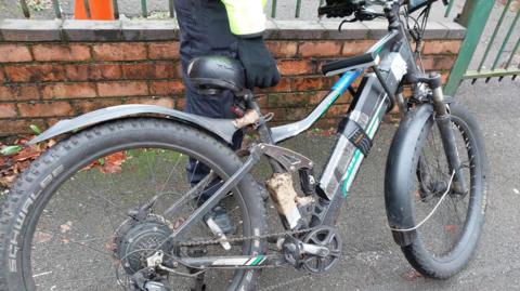 An illegally modified e-bike being held by a police officer after being seized