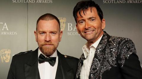 Two man, Ewan McGregor and David Tennant, pictured with the Bafta Scotland backdrop