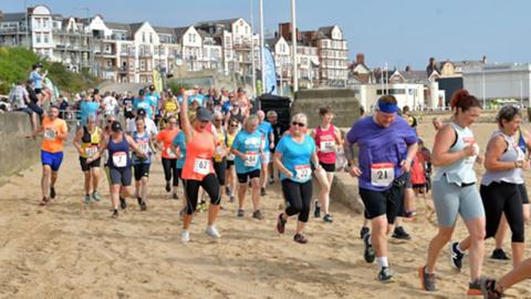 Competitors wearing racing gear run along the beach at Bridlington