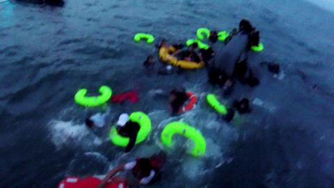 Yellow and red life-bands in the sea as people try and cling on to them. The picture is slightly blurry as it has been taken from a bodyworn camera.