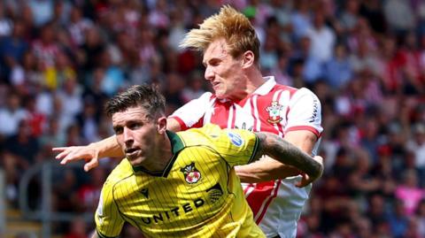 Flynn Downes of Southampton wins a header ahead of Josh Windass during Southampton's game against Wrexham last August