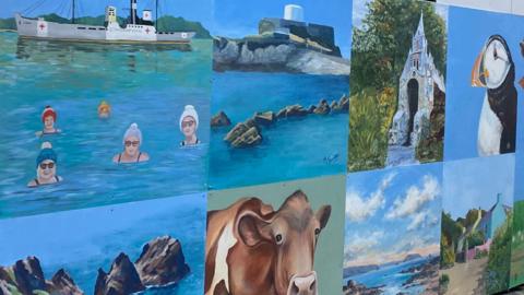 A montage of eight different paintings which show sea swimmers by a boat, a rocky outcrop in a bay, a church, a puffin, another rocky outcrop in the, a brown and white cow, a vista of sea and headlands with a pastel-coloured sky and a green house with a pink wall. 