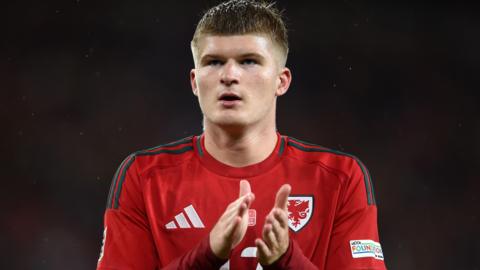 Jordan James applauds in Wales kit