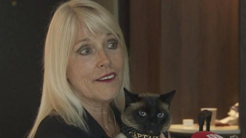 Holly Hennessey holding her Siamese cat, Captain.