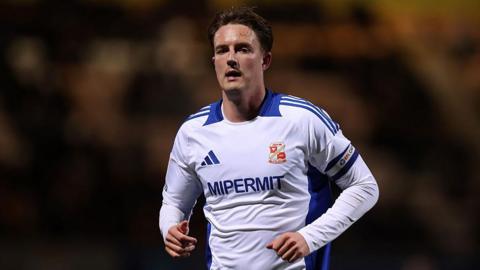 Will Wright looking forward while running and wearing Swindon Town's white and blue away kit