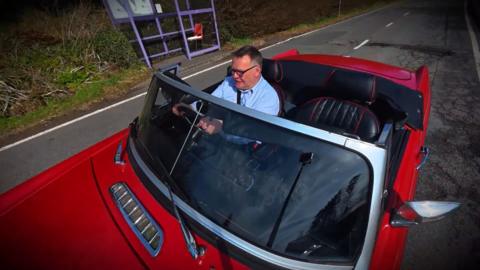 Alasdair MacLeòid a' dràibheadh càr spaideal deag