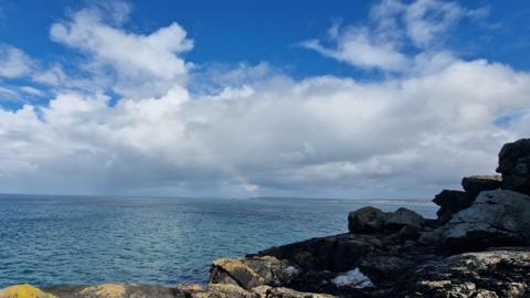 Rocky shore and sea, with cloudy sky above