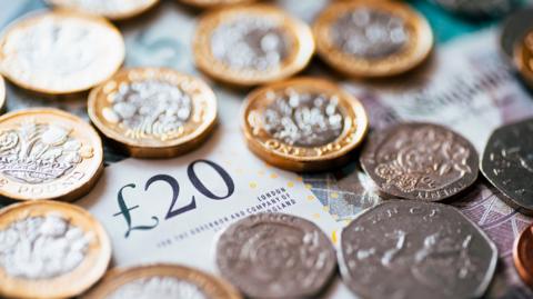 British pound coins scattered across a 20 pound note.