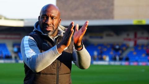 Port Vale manager Darren Moore claps the fans as he walks off the pitch after a game 