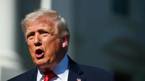 Donald Trump speaking to reporters at the White House on Saturday, he is wearing a dark suit and red tie
